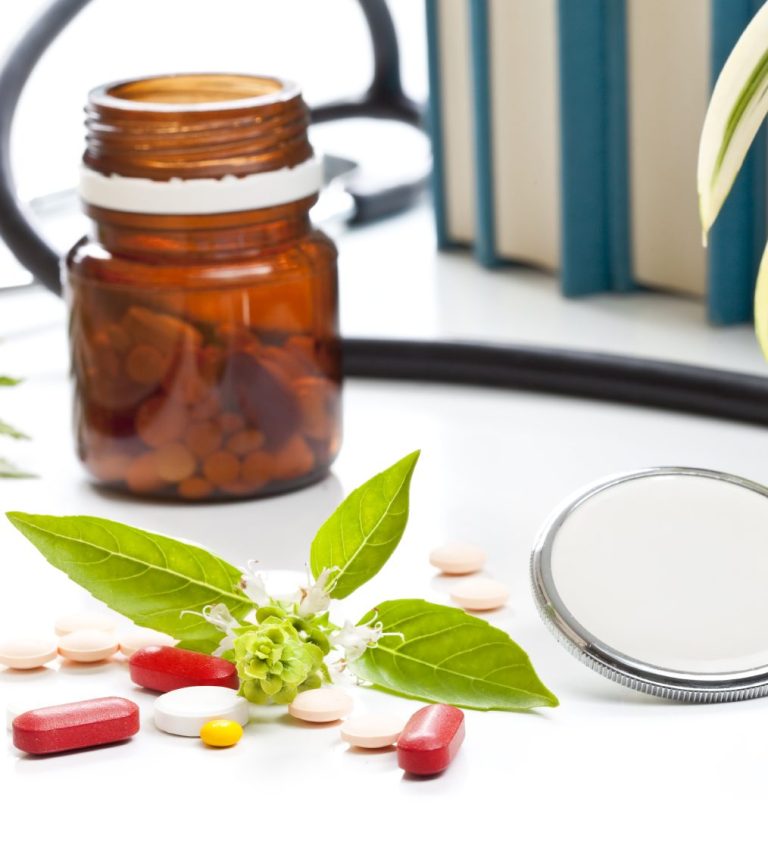 Supplements and basil in front of a light protected medicine bottle that is open. Stethoscoe visible again. 