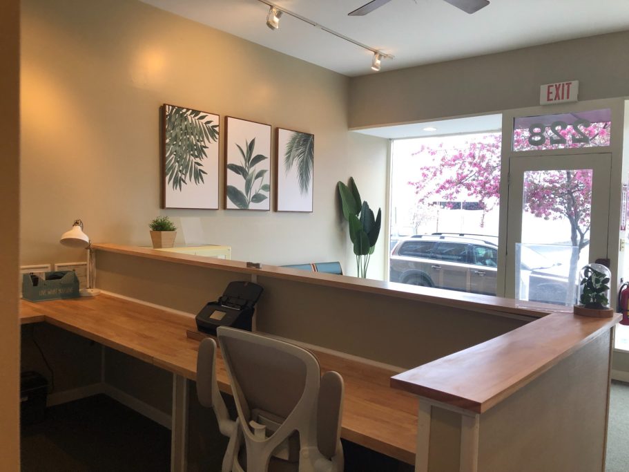Reception Image of reception desk looking out towards the street. The desk is made of rubberwood and there are succulent decorations and wall art.