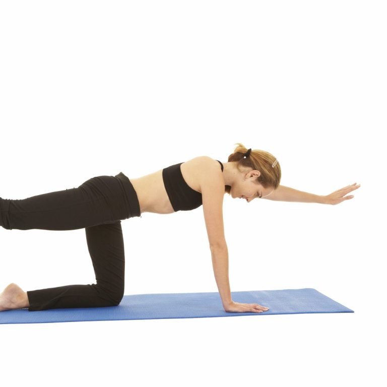 Human in black bra and pants performing bird-dog strengthening on blue yoga mat. 