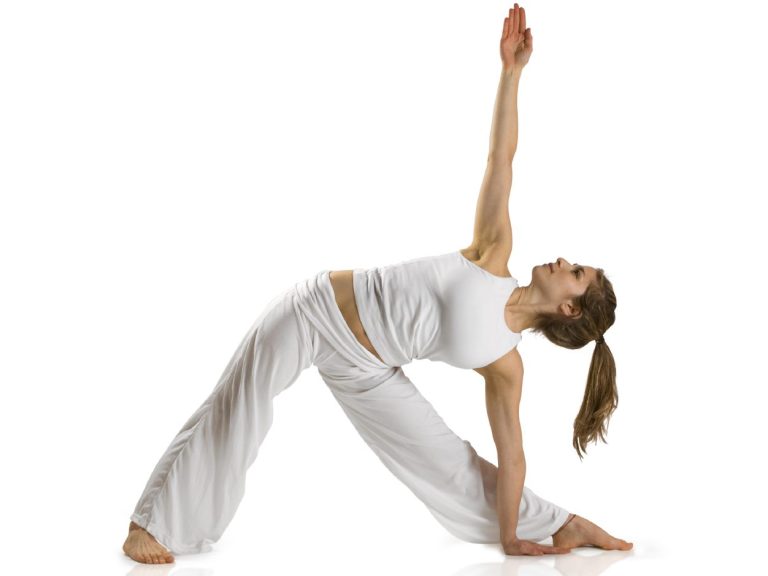 Image of human with long hair doing yoga stretching with abducted hips and arms at 90 degrees. She is laterally flexing to the left and looking up. Wearing white. 